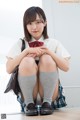 A young woman in a school uniform sitting on the floor.